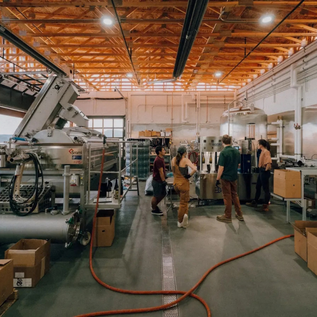Group of people standing insdie a distillery.