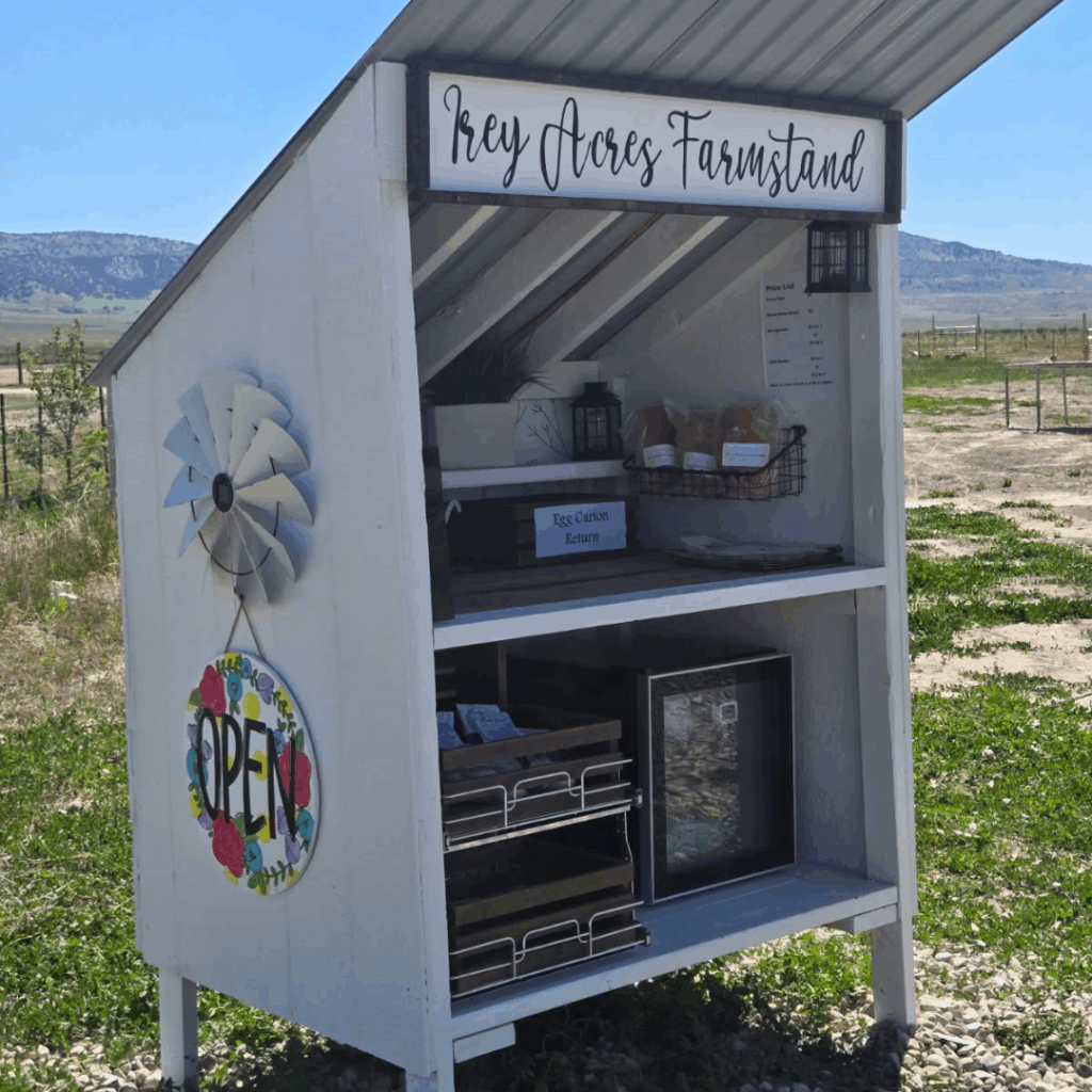 A small, white roadside farmstand building labeled 