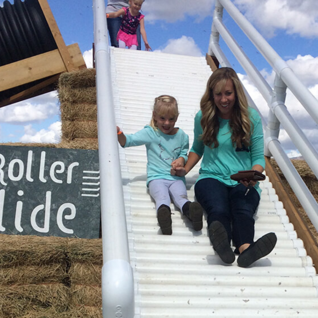 Woman and young girl slide down a roller slide